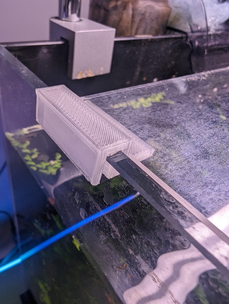 May include: A white 3D printed aquarium accessory for holding a glass rod or other aquarium equipment.