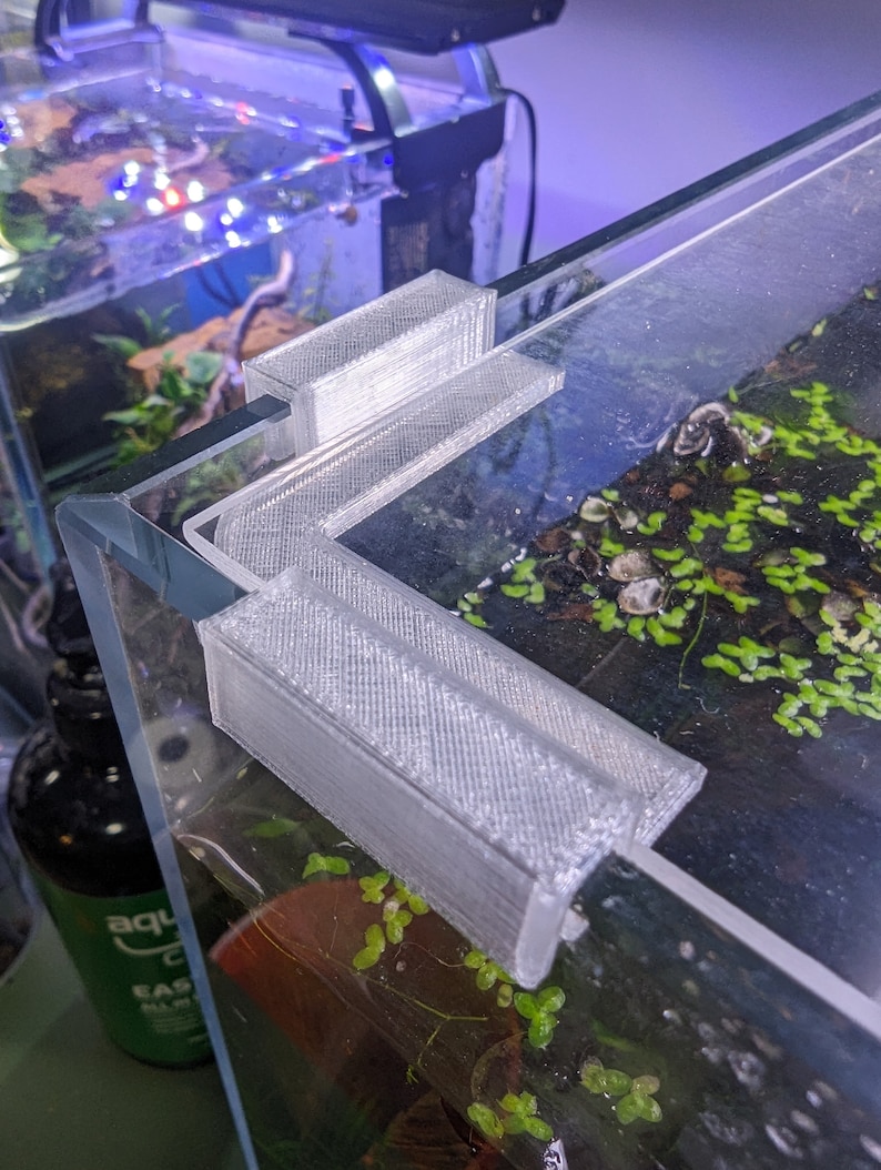 May include: A white 3D printed corner brace for an aquarium tank. The brace is designed to fit in the corner of the tank and help to support the glass.