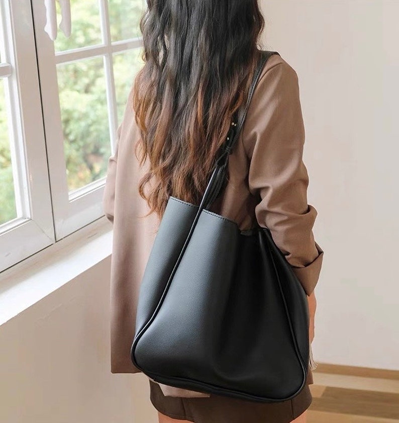 A women model is wearing a black leather shoulder bag for everyday use and laptop