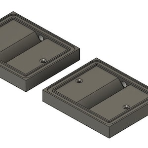 Könnte beinhalten: Zwei graue, rechteckige Metallblöcke mit einer vertieften Fläche in der Mitte. Jeder Block hat zwei kleine Löcher auf der Oberseite.