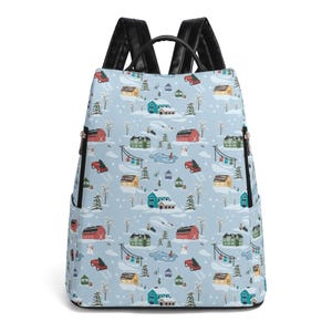 May include: A blue backpack with a winter village print. The print features houses, trees, and snowmen. The backpack has black straps and a zipper closure.