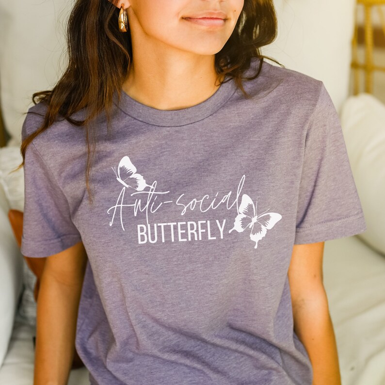 May include: A purple t-shirt with the text "Anti-social Butterfly" in white lettering and two white butterfly graphics.