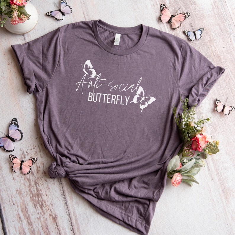 May include: A purple t-shirt with the text "Anti-social Butterfly" and two white butterfly silhouettes.