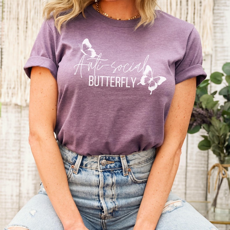 May include: A purple t-shirt with the text "Anti-social Butterfly" and two white butterfly graphics.
