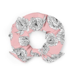 May include: A pink scrunchie with a white floral pattern. The scrunchie is made of a soft, stretchy fabric and is perfect for holding hair in place.