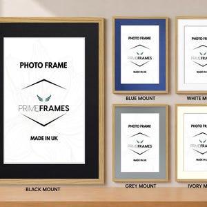 May include: A selection of photo frames with different mount colours: black, blue, white, grey, and ivory. Each frame has a light wood-effect border and displays the text "PHOTO FRAME" and "PRIME FRAMES MADE IN UK".
