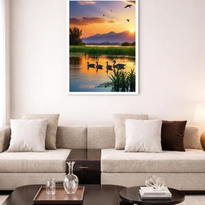 May include: A framed wall art print featuring a sunset landscape with four ducks swimming in a calm lake. The scene includes green reeds in the foreground, distant mountains, and a golden sky with birds flying above the water surface.