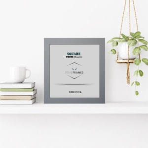 May include: A grey square photo frame with the text "SQUARE PHOTO FRAMES" and "PRIME FRAMES". The text "MADE IN UK" is at the bottom. A white mug and books are on the left. A hanging plant is on the right.