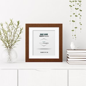 May include: A square photo frame with a dark brown wood grain finish and a white mat board. The center insert features the text SQUARE PHOTO FRAMES, the logo PRIME FRAMES with a small wing icon, and the text MADE IN UK in black lettering.