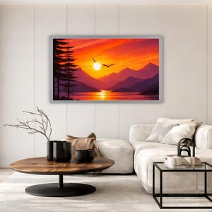 May include: A rectangular wall art print featuring a vibrant sunset over a mountain range and a calm lake. The scene includes silhouettes of tall pine trees on the left, a bright yellow sun, and two birds flying in a sky filled with orange and red hues.