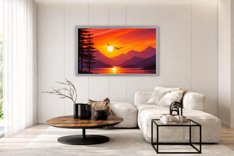 May include: A rectangular wall art print featuring a vibrant sunset over a mountain range and a calm lake. The scene includes silhouettes of tall pine trees on the left, a bright yellow sun, and two birds flying in a sky filled with orange and red hues.