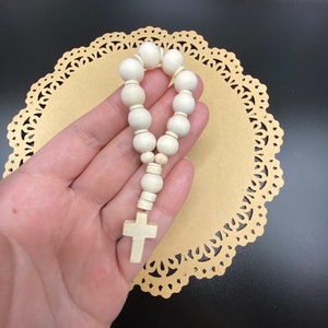 May include: A white wooden rosary with a white wooden cross charm.