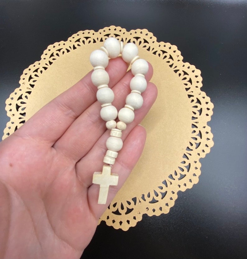 May include: A white wooden rosary with a white wooden cross charm.