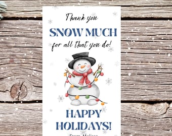 May include: A white holiday card with a snowman illustration and the text "Thank you SNOW MUCH for all that you do! HAPPY HOLIDAYS!" on a wooden background with pine branches.
