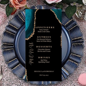 May include: A black and teal menu card with gold glitter accents. The menu lists appetizers, entrees, desserts, and drinks for a 40th birthday party. The text reads "Krystal's 40th Birthday May 29, 2022".