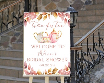May include: A white sign with a watercolor design of teacups and fall leaves. The text on the sign reads "Time for Tea" and "Welcome to Melissa's Bridal Shower 04.25.23".