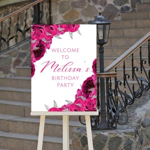 Puede incluir: Un cartel blanco con un diseño floral rosa y el texto "Bienvenido a la fiesta de cumpleaños de Melissa". El cartel está en un caballete de madera.