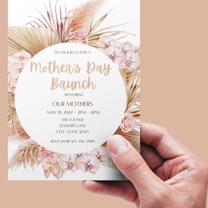 May include: A white invitation card with a pink and beige floral design. The text on the card reads "Please join us for a Mother's Day Brunch honoring our mothers. May 19, 2022 - 2PM - 6PM. The Lounge, 123 Baby Lane, City, State 12345. RSVP: Jamie 123-456-7880."