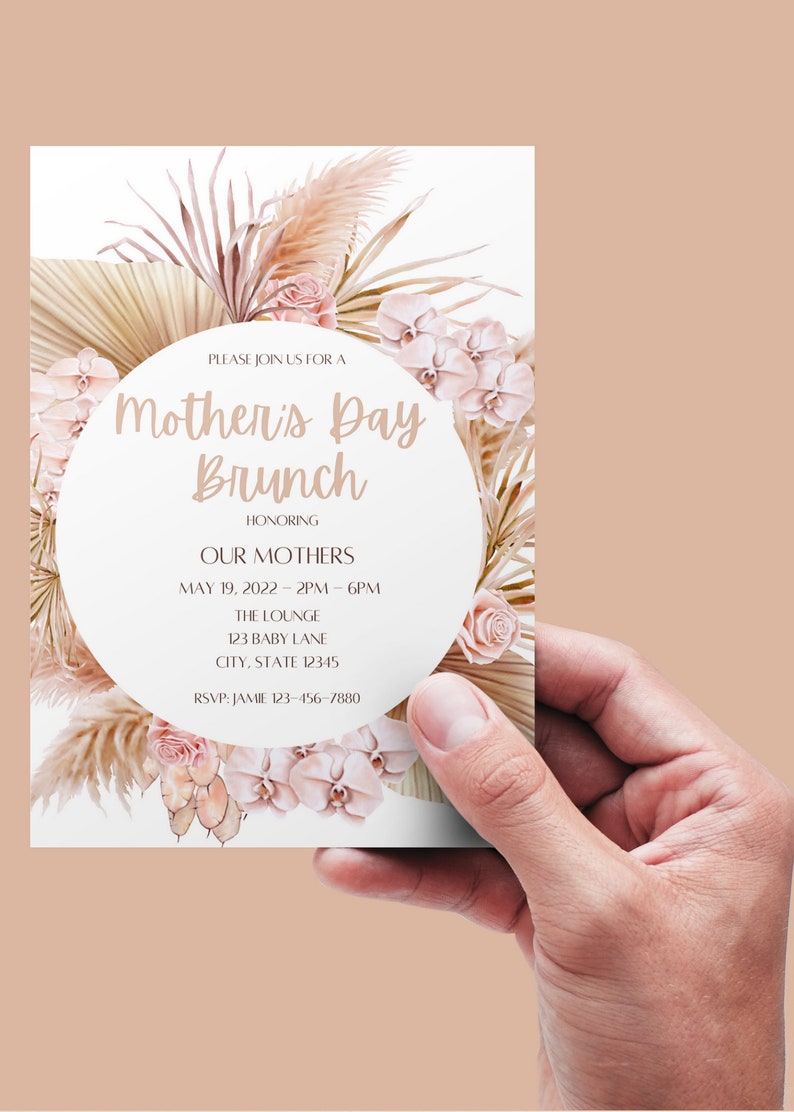 May include: A white invitation card with a pink and beige floral design. The text on the card reads "Please join us for a Mother's Day Brunch honoring our mothers. May 19, 2022 - 2PM - 6PM. The Lounge, 123 Baby Lane, City, State 12345. RSVP: Jamie 123-456-7880."