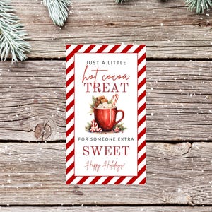 以下が含まれることがあります： 白地に赤と白のストライプのギフトタグ。タグには、マシュマロ、キャンディーケーン、シナモンスティックを入れたホットココアのマグカップの水彩画が描かれています。タグのテキストは「Just a little hot cocoa treat for someone extra sweet. Happy Holidays!」です。