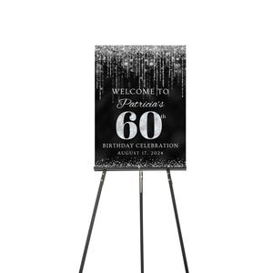 May include: Black and silver welcome sign with a silver glitter background. The sign says "Welcome to Patricia's 60th Birthday Celebration August 17, 2024". The sign is on a black easel.