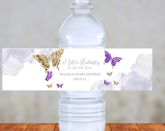 May include: Water bottle label with a purple and gold butterfly design. The text reads "A little Butterfly is on the way Melissa's Baby Shower 08.21.23".