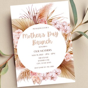 May include: A white invitation with a floral design featuring pink orchids, beige pampas grass, and a circle with the text "Mother's Day Brunch" in brown lettering. The invitation includes details for a brunch honoring mothers on May 19, 2022, from 2 PM to 6 PM at The Lounge, 123 Baby Lane, City, State 12345. RSVP to Jamie at 123-456-7880.