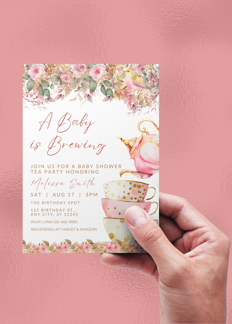 May include: A pink and gold baby shower invitation with a teapot and teacups. The invitation reads "A Baby is Brewing" and includes the date, time, and location of the event. RSVP information is also included.