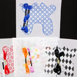 Può includere: Tele per punto croce con vari disegni, tra cui un motivo floreale blu, vortici rossi e diamanti bianchi e neri. Ogni tela ha un fascio di filo da ricamo colorato attaccato, pronto per essere cucito.
