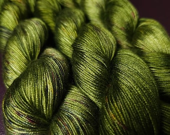 Könnte beinhalten: Nahaufnahme eines Knäuels grüner Wolle mit Farbflecken. Die Wolle ist weich und texturiert und perfekt zum Stricken oder Häkeln.