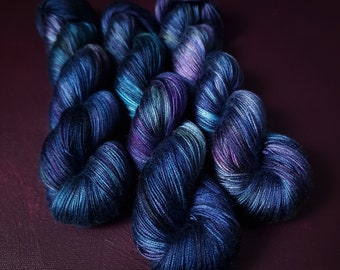 May include: Three skeins of yarn in shades of blue, green, and purple. The yarn is hand-dyed and has a variegated colour pattern.