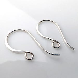 May include: Two silver-colored earring hooks. Each hook has a curved top and a small loop at the bottom. The hooks are made of a shiny, smooth metal and are set against a white background.