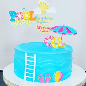 May include: A blue and white pool-themed cake with a white ladder, flip flops, a beach ball, and a pink and blue umbrella. The cake is decorated with the words "Pool Party" and "Sandara 8 Anos" and "Serena 5 Anos".