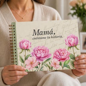 Może przedstawiać: Spiralnie oprawiony notatnik z kwiatowym wzorem z różowymi piwoniami i napisem "Mamá, cuéntame tu historia." Notatnik ma jasną zieloną grzbiet i złote spiralne wiązanie. Tło jest kremowe z pismem.
