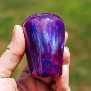 Puede incluir: Un pomo de palanca de cambios morado iridiscente hecho a mano. El pomo de resina presenta tonos arremolinados de morado, azul y rosa, creando un diseño único y llamativo. La forma suave y redondeada está diseñada para un manejo cómodo.