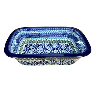 May include: Rectangular ceramic baking dish with a dark blue rim and a floral pattern in shades of blue and green. The dish has a slightly curved shape and is designed for baking and serving.