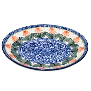 May include: A large, round, blue and white ceramic serving platter with a floral design. The platter features a border of pink flowers with green leaves on a white background. The center of the platter is a blue and white swirl pattern.