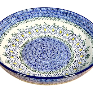 Puede incluir: Un cuenco redondo de cerámica con interior blanco y borde azul. El cuenco está decorado con un estampado de margaritas y un diseño de remolino azul. El cuenco tiene aproximadamente 30 cm de diámetro.