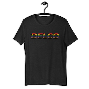 Peut inclure: Un t-shirt noir avec le mot "DELCO" imprimé en couleurs arc-en-ciel.