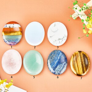 May include: Seven smooth, oval-shaped stones in various colors and patterns. The stones are arranged in a grid pattern on a light orange background. The stones are labeled with numbers 1 through 7.
