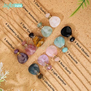 May include: A collection of gemstone pendant necklaces. Each necklace features a gold chain and a unique gemstone pendant, including Clear Quartz, Green Aventurine, Tiger Eye, and Amethyst. The pendants are labeled with their respective names.