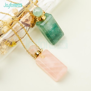 Puede incluir: Dos collares de cadena dorada con colgantes de botella de cristal. Un colgante es verde y el otro es rosa.