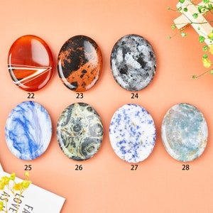 May include: Set of 7 oval-shaped polished stones with various patterns and colors, including blue, green, red, black, and white. The stones are numbered 22 through 28.