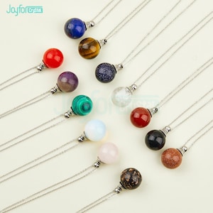 Może przedstawiać: Kolekcja 12 naszyjników z różnokolorowymi kulami z kamieni szlachetnych. Każdy naszyjnik ma srebrny łańcuszek i srebrne zapięcie. Kamienie szlachetne obejmują czerwony, niebieski, zielony, fioletowy, brązowy, czarny, biały i przezroczysty.