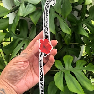 May include: A black and white tribal design sticker with a red hibiscus flower. The sticker is on a white background.