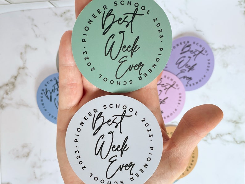 K&ouml;nnte beinhalten: Ein Satz von f&uuml;nf runden Aufklebern mit dem Text "Pioneer School 2023. Pioneer School" und "Best Week Ever" in schwarzer Schrift. Die Aufkleber sind in verschiedenen Farben, darunter Gr&uuml;n, Lila, Rosa, Blau und Beige.