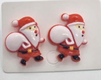 May include: A pair of red and white Santa Claus earrings. Each earring features a Santa Claus carrying a white bag with a red and yellow belt.