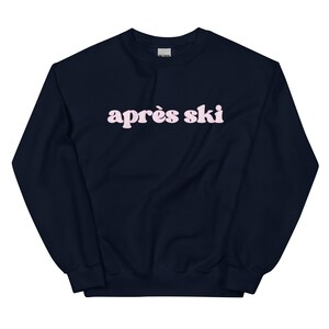 Op de afbeelding: Een donkerblauw sweatshirt met de tekst "apr&egrave;s ski" in roze letters.