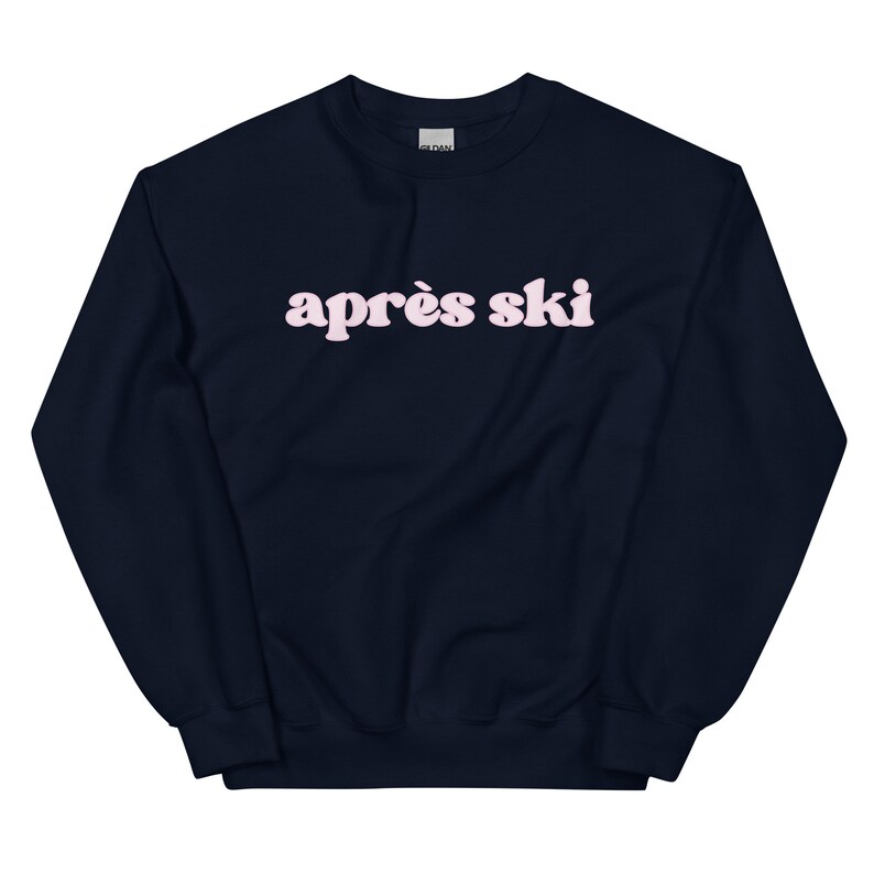 Op de afbeelding: Een donkerblauw sweatshirt met de tekst "apr&egrave;s ski" in roze letters.
