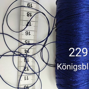 Puede incluir: Una bobina de hilo azul oscuro con el n&uacute;mero 229 y la palabra "K&ouml;nigsblau" impresa en ella.